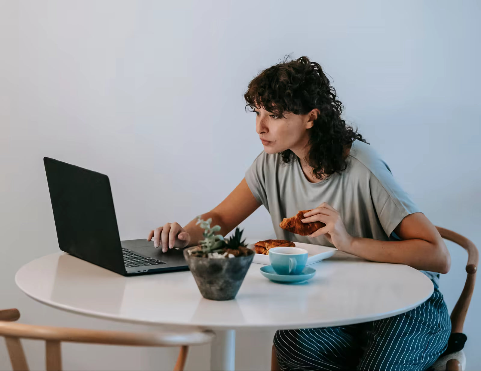 Woman having breakfast while working on a laptop