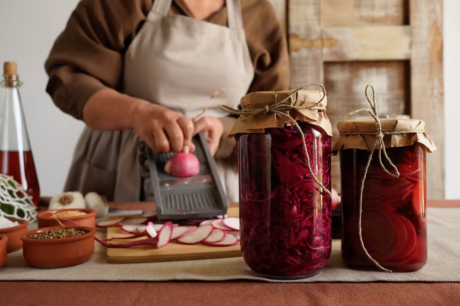 Person preparing homemade fermented vegetables in jars