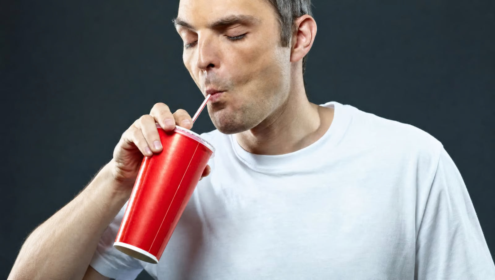 Man drinking a sugary fizzy soda through a straw from a large cup